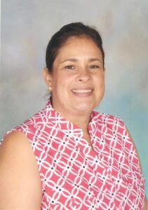 Smiling woman in patterned pink blouse.