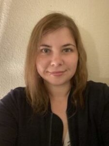 Smiling woman in a dark jacket indoors.